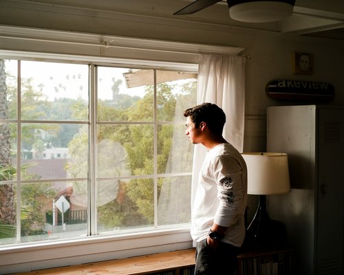Person standing by a large window looking outside to rest during a workday